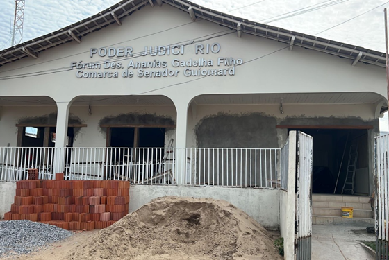 Na imagem prédio do Fórum de Senador Guiomard que está em reforma. Na imagem encontram-se também materiais de construção como tijolos, areia e brita