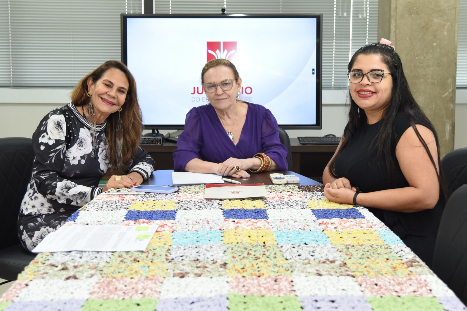 Foto da presidente do TJAC, desembargadora Regina Ferrari, em reunião. Além da magistrada, na imagem, ao redor de uma mesa, há uma representante do Instituto Mulheres da Amazônia e uma da empresa Onélia Abreu da Rocha.