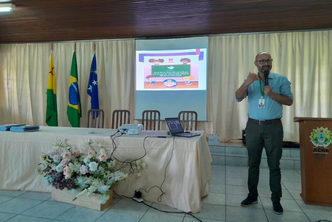 Imagem feita em escola do município de Cruzeiro do Sul, localizado à 636 quilômetros da Capital, Rio Branco. Onde mostra palestrante conversando com servidoras e servidores sobre o projeto “Justiça Restaurativa nas Escolas”. Equipe do TJAC apresenta projeto “Justiça Restaurativa nas Escolas” para colégios de Cruzeiro do Sul Planos de trabalho estão sendo desenvolvidos com as seis unidades escolares públicas selecionadas para participar da iniciativa A equipe do Núcleo Permanente de Justiça Restaurativa (NUPJR) do Tribunal de Justiça do Acre (TJAC) realizou na última quinta-feira, 11, no auditório do Núcleo da Secretaria de Educação do Acre, uma palestra de apresentação do projeto “Justiça Restaurativa nas Escolas” para as diretoras e diretores dos colégios de Cruzeiro do Sul que farão parte desta iniciativa. Segundo a servidora do NUPJR, Mirlene Taumaturgo, a ação além de atender ao Termo de Cooperação estabelecido entre o Ministério da Educação e o Conselho Nacional de Justiça (CNJ), oportuniza o cultivo de habilidades resolutiva dentro da comunidade escolar, relevante para solução de pequenos conflitos. Nesta primeira edição do projeto na cidade de Cruzeiro do Sul, foram selecionadas para participar as escolas públicas: Dom Henrique Ruth, Professor Flodoardo Cabral, João Kubitschek, Absolon Moreira, Craveiro Costa e Professora Quita. Diálogo entre servidores Durante a estadia em Cruzeiro do Sul, a equipe do NUPJR dialogou sobre o impacto positivo da implementação de competências da justiça restaurativa no ambiente de trabalho, com as servidoras da comarca de Cruzeiro do Sul, Rozélia Moura e Rasmilda Melo, ambas integrantes do curso de formação em justiça restaurativa voltado para o Judiciário.